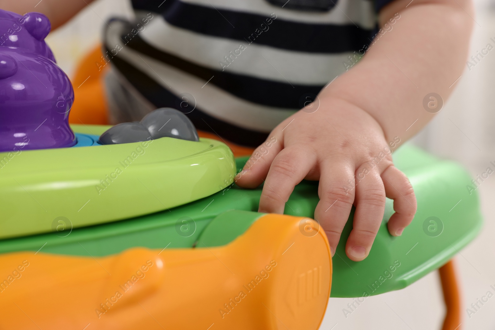 Photo of Little baby playing with toy walker, closeup