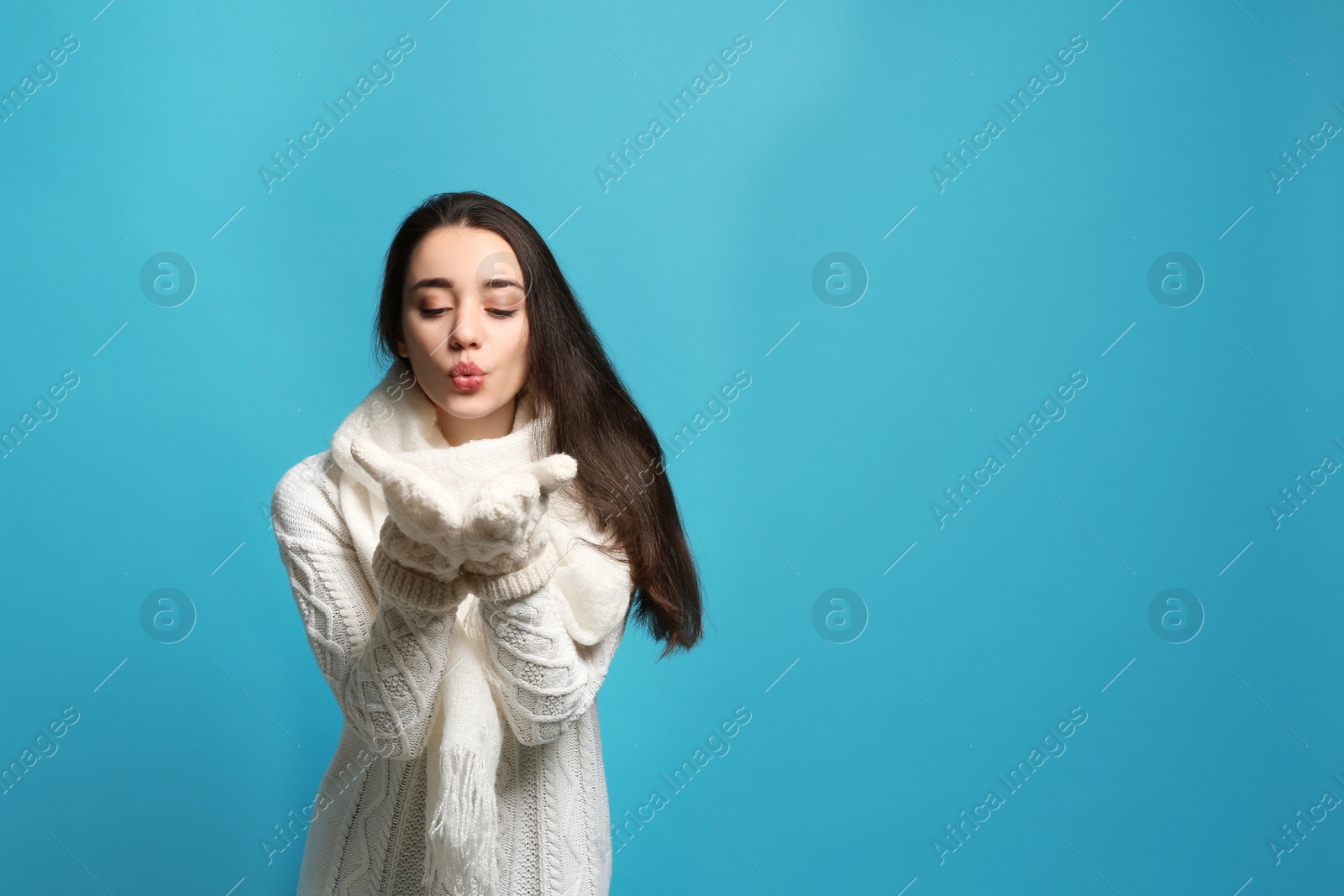 Photo of Young woman wearing warm clothes on color background, space for text. Winter season