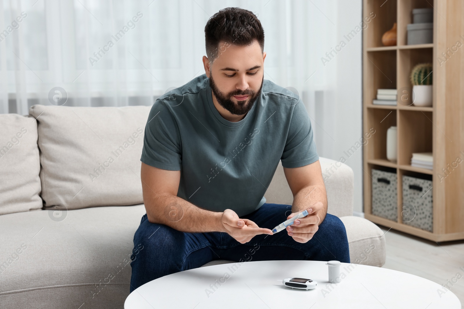 Photo of Diabetes test. Man checking blood sugar level with lancet pen at home