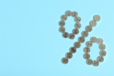 Photo of Percent sign made of Ukrainian hryvnia coins on turquoise background, flat lay. Space for text