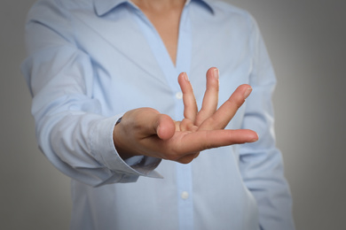 Photo of Woman showing something against grey background, focus on hand