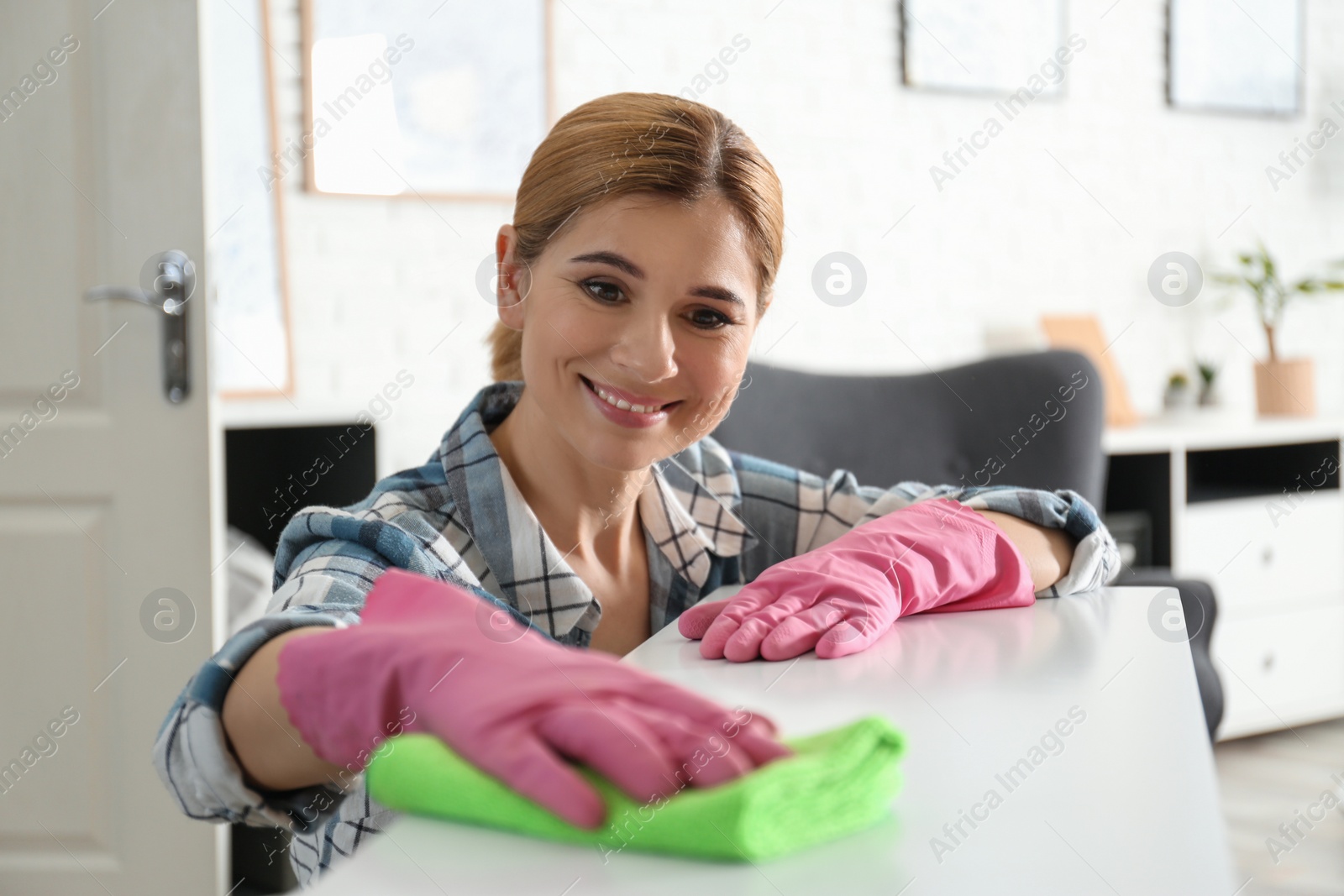 Photo of Portrait of woman cleaning table with rag in living room