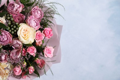 Photo of Beautiful bouquet with roses on light blue background, closeup. Space for text