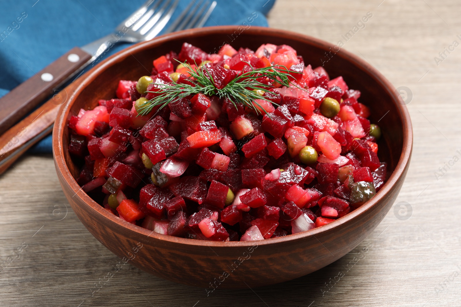 Photo of Bowl of delicious fresh vinaigrette salad on wooden table, closeup