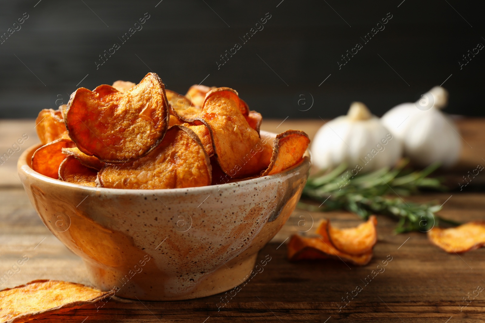 Photo of Delicious sweet potato chips in bowl on table. Space for text