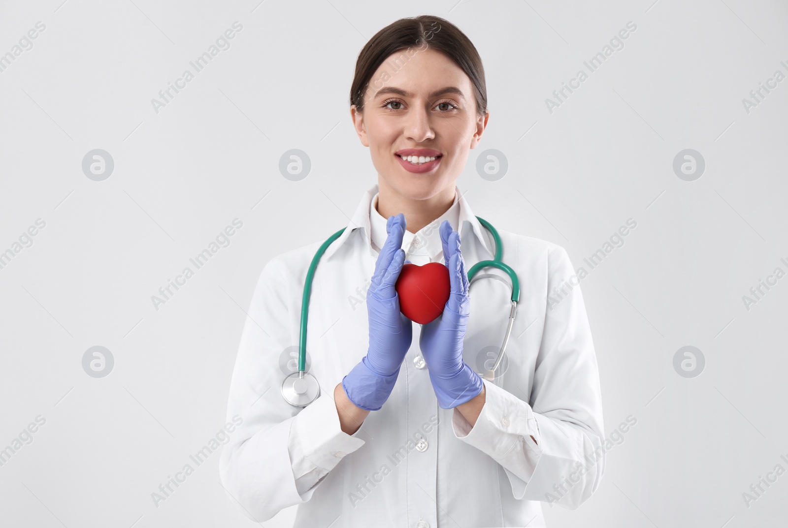 Photo of Doctor with stethoscope and red heart on white background. Cardiology concept