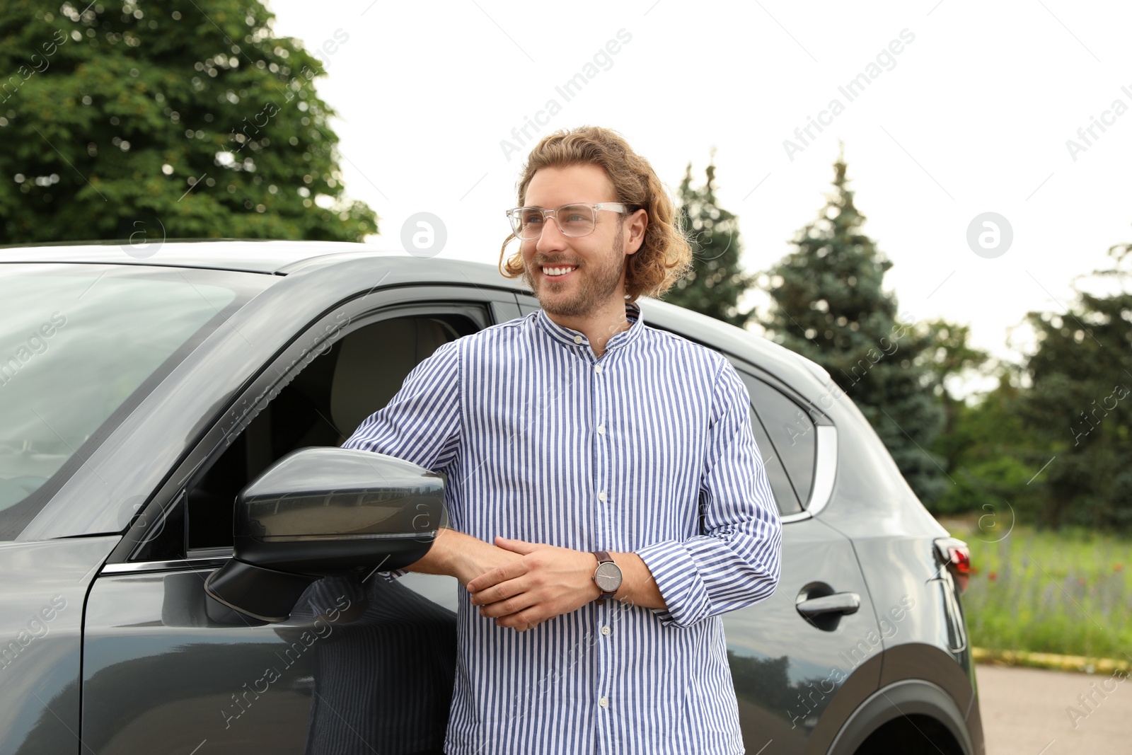 Photo of Attractive young man near luxury car outdoors