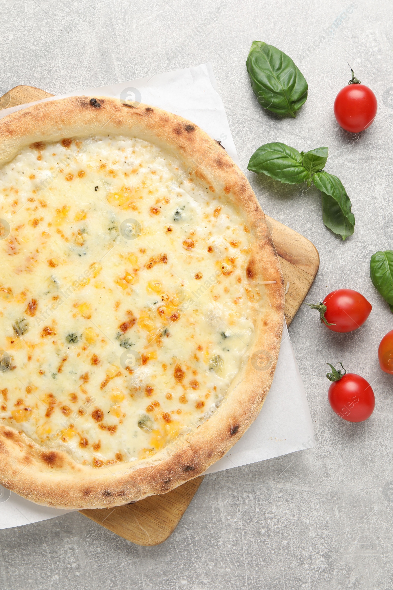 Photo of Delicious cheese pizza, basil and tomatoes on light grey table, flat lay