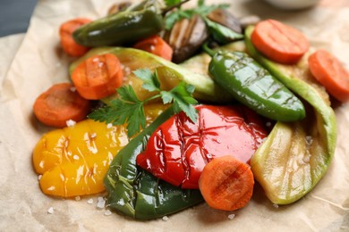 Photo of Delicious grilled vegetables with parsley on parchment, closeup