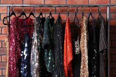 Photo of Rack with collection of fashionable dresses near brick wall in showroom. Preparing for party