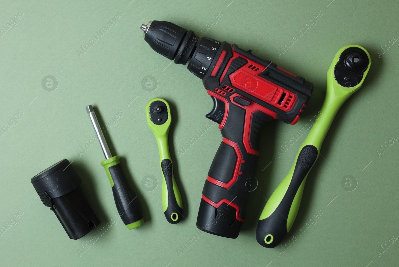 Photo of Electric screwdriver and accessories on pale green background, flat lay