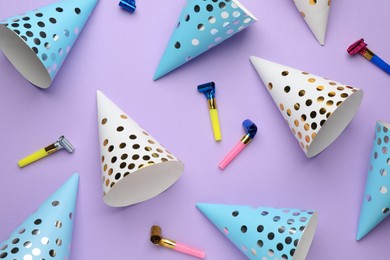 Bright party hats and horns on lilac background, flat lay
