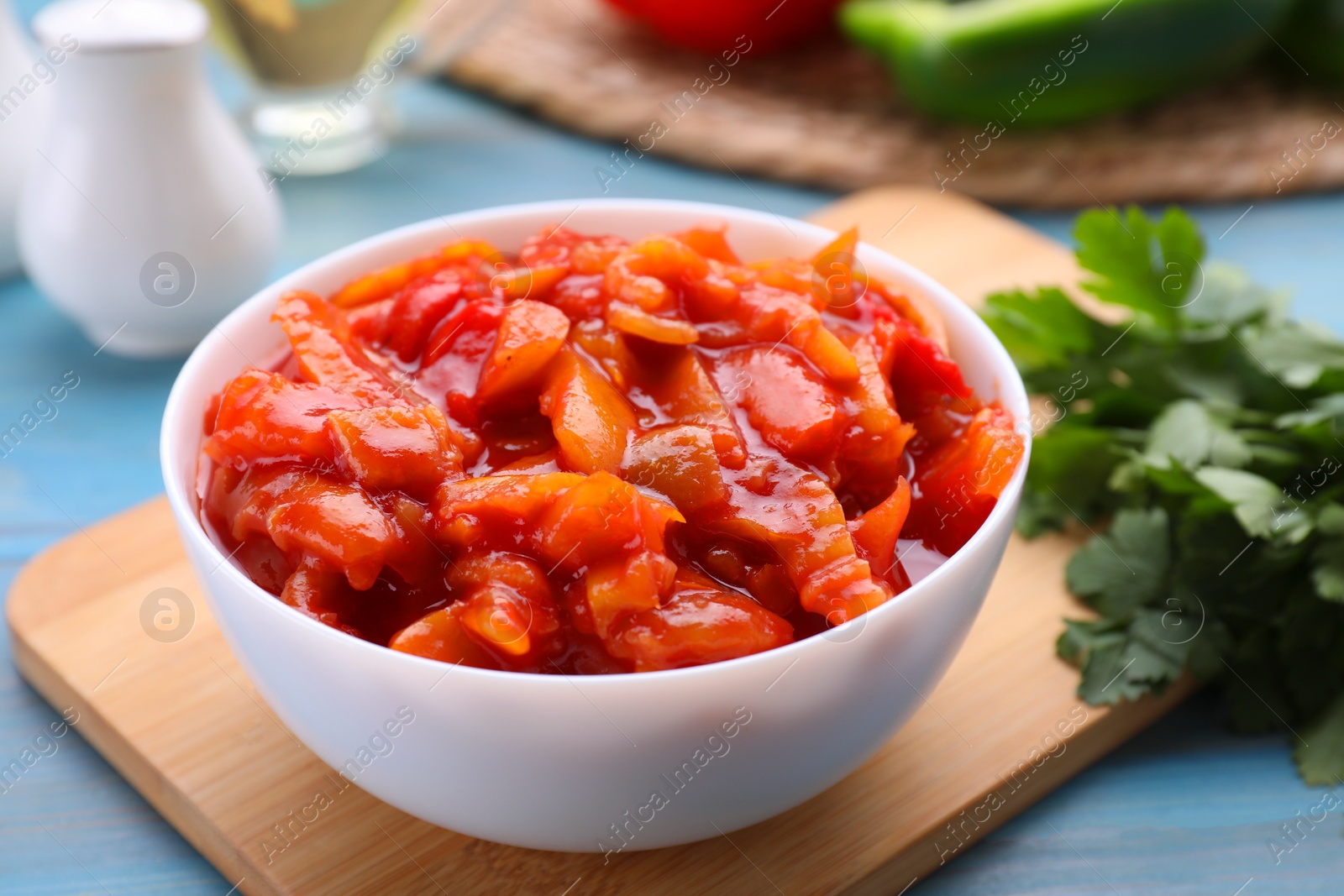 Photo of Bowl of delicious lecho on light blue wooden table, closeup