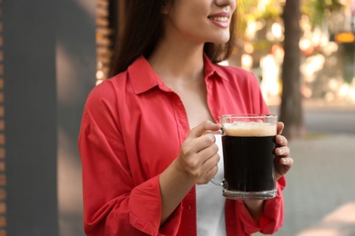 Photo of Young woman with cold kvass outdoors, closeup. Traditional Russian summer drink