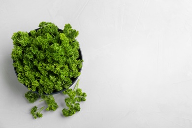 Fresh curly parsley in bowl on light grey table, flat lay. Space for text