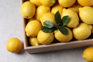 Photo of Fresh lemons in wooden crate on grey table, above view