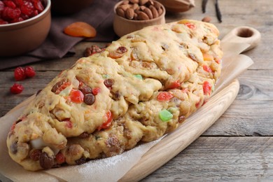 Photo of Unbaked Stollen with candied fruits and raisins on wooden table, closeup