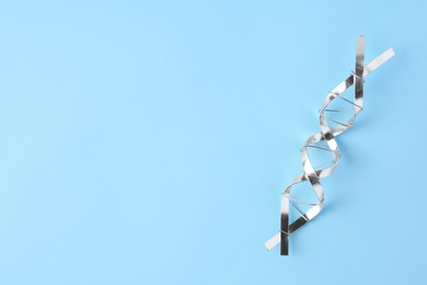 Photo of DNA molecular chain model made of metal on light blue background, top view. Space for text