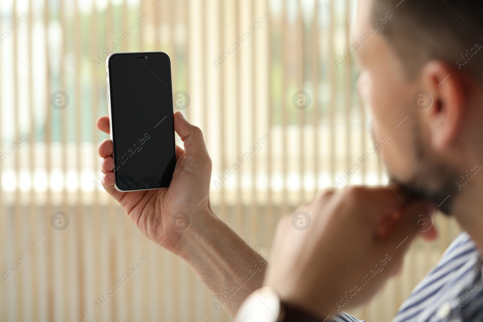 Photo of Man using smartphone near window indoors, closeup view