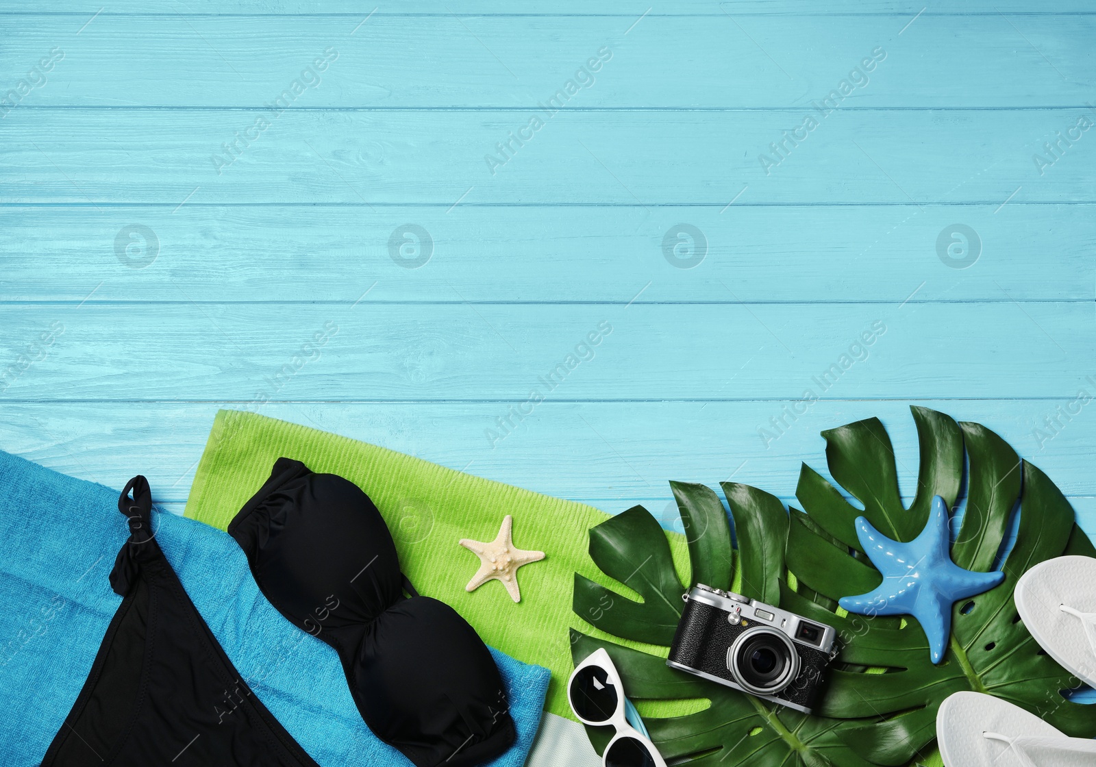 Photo of Flat lay composition with swimsuit and beach accessories on wooden background. Space for text