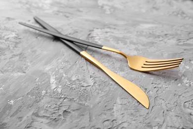 Photo of Elegant cutlery. Stylish knife and fork on grey textured table, closeup