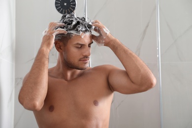 Handsome man washing hair in shower at home