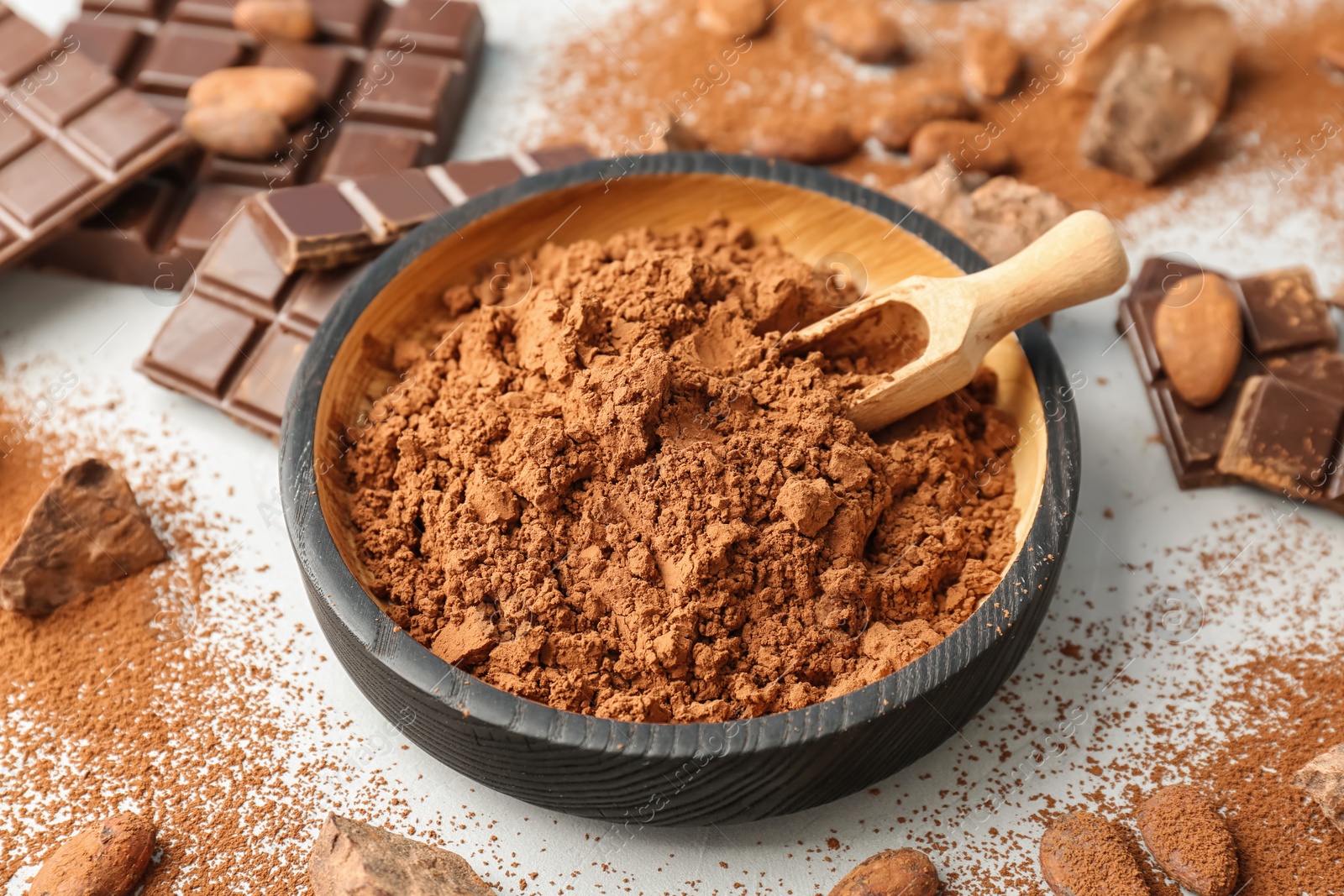 Photo of Composition with cocoa powder, beans and chocolate on light background