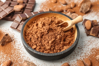 Photo of Composition with cocoa powder, beans and chocolate on light background