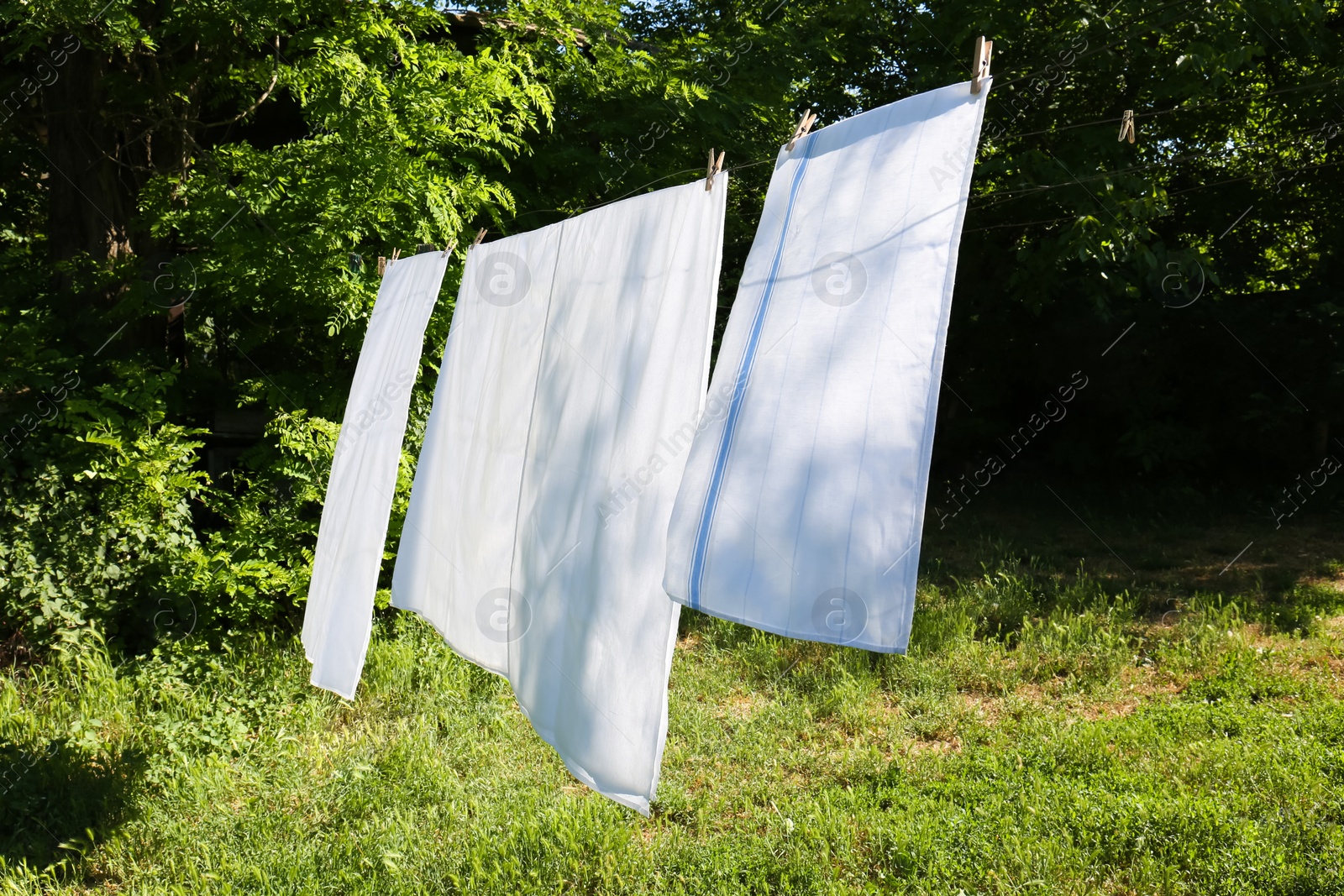 Photo of Washing line with clean laundry and clothespins outdoors