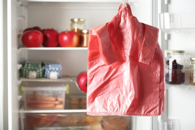 Photo of Many plastic bags near refrigerator with products. Space for text