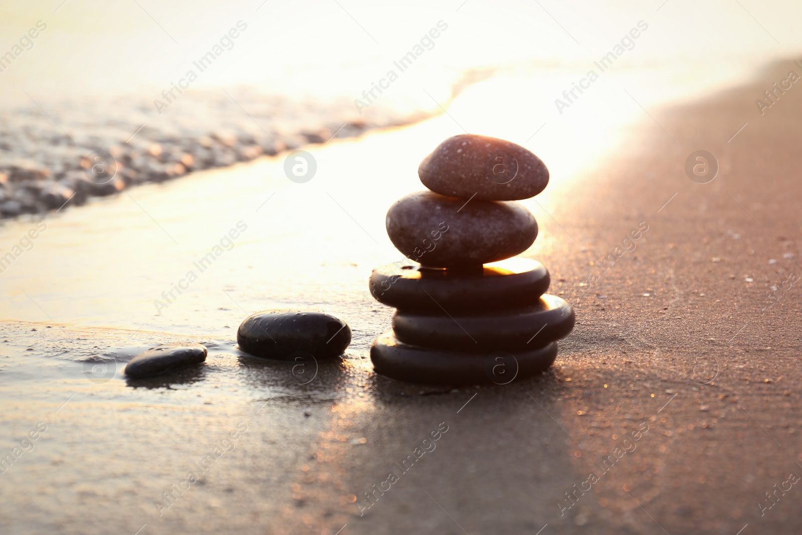 Photo of Dark stones on sand near sea at sunset, space for text. Zen concept