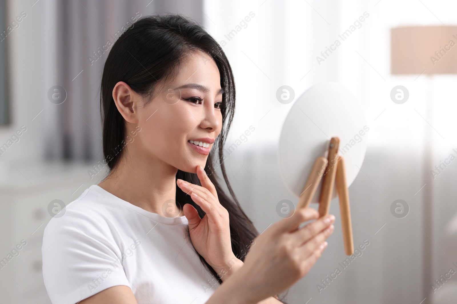 Photo of Woman with perfect skin looking at mirror indoors