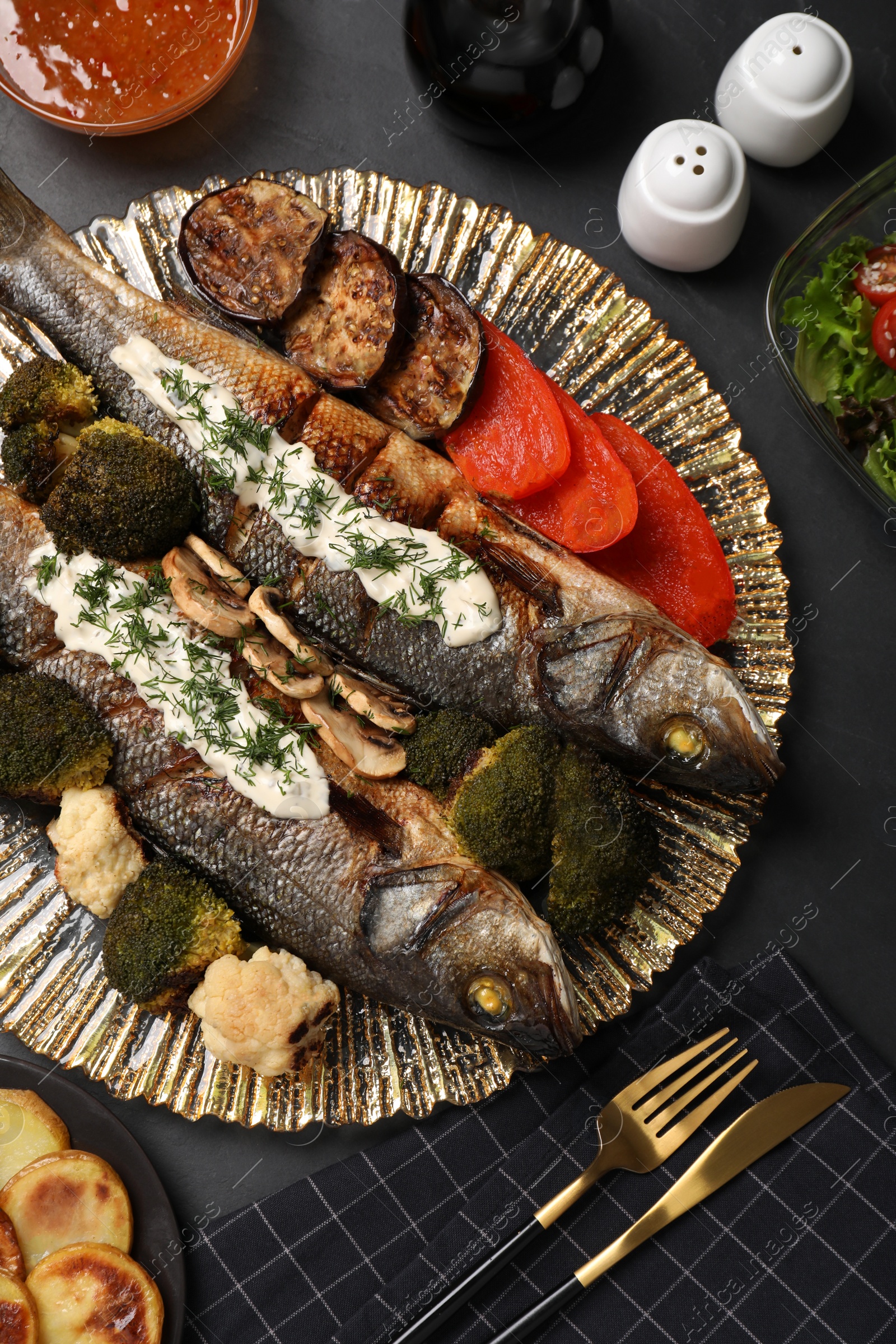 Photo of Flat lay composition with delicious sea bass fish served on dark grey table