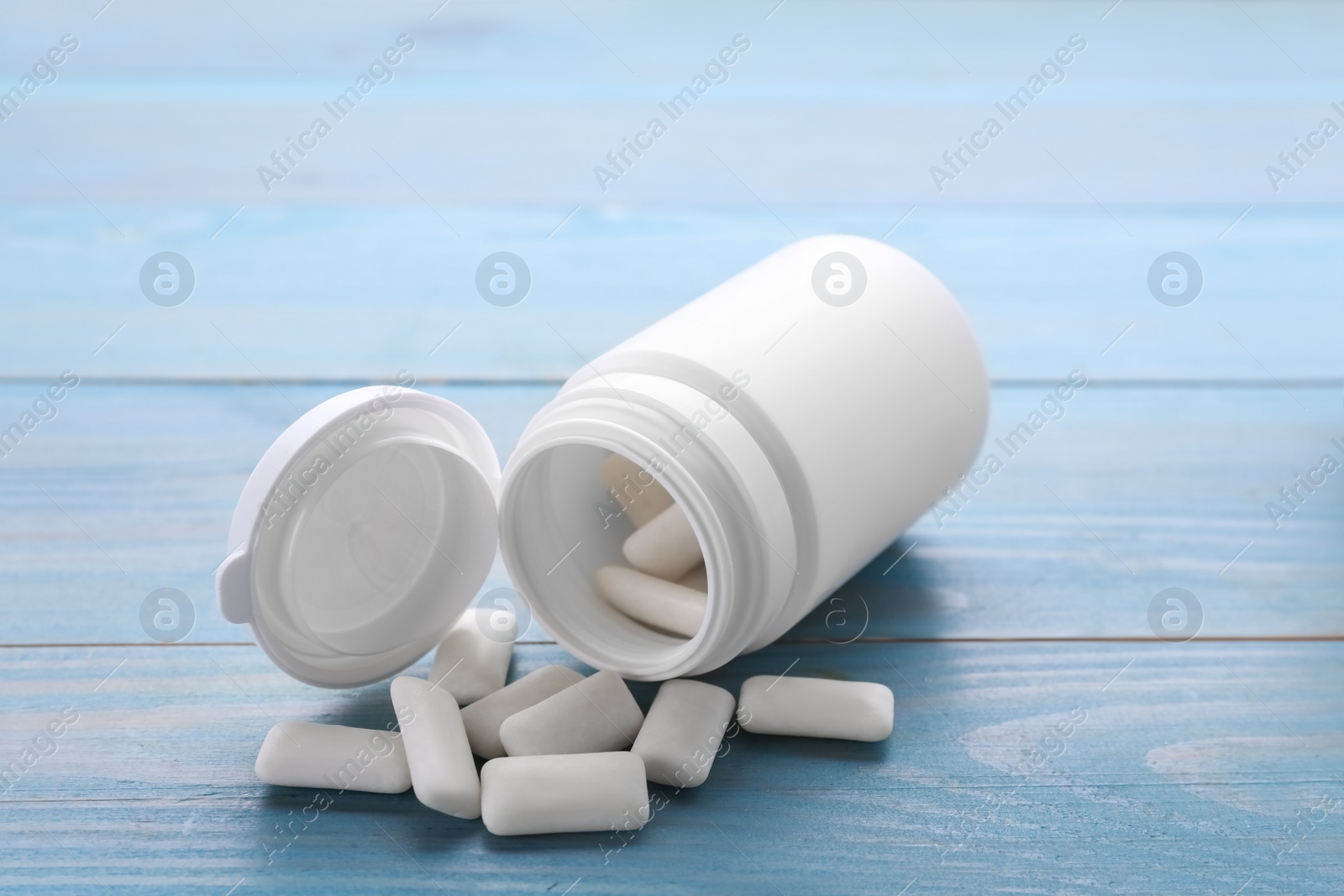 Photo of Jar with chewing gums on light blue wooden table