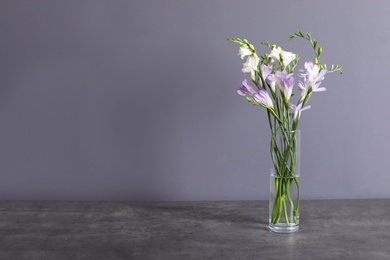 Photo of Beautiful fragrant freesia flowers in vase and space for text on color background