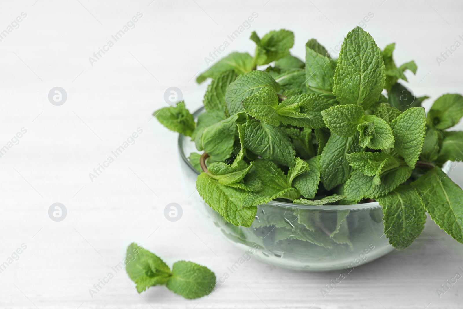 Photo of Glass bowl with fresh green mint on table. Space for text