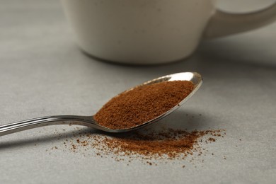 Photo of Spoon of chicory powder on light grey table, closeup