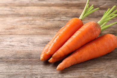 Photo of Fresh juicy carrots on wooden background, closeup. Space for text