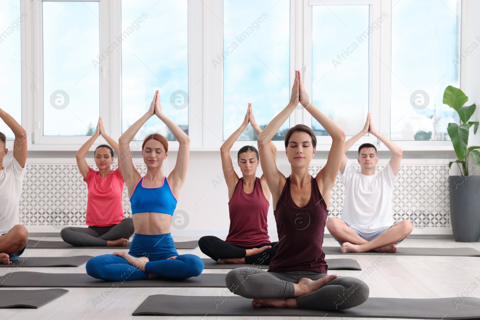 Photo of Group of people practicing yoga on mats indoors