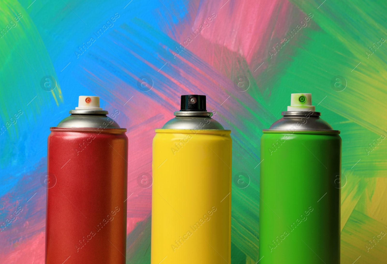 Photo of Cans of different spray paints on color background, closeup. Graffiti supplies