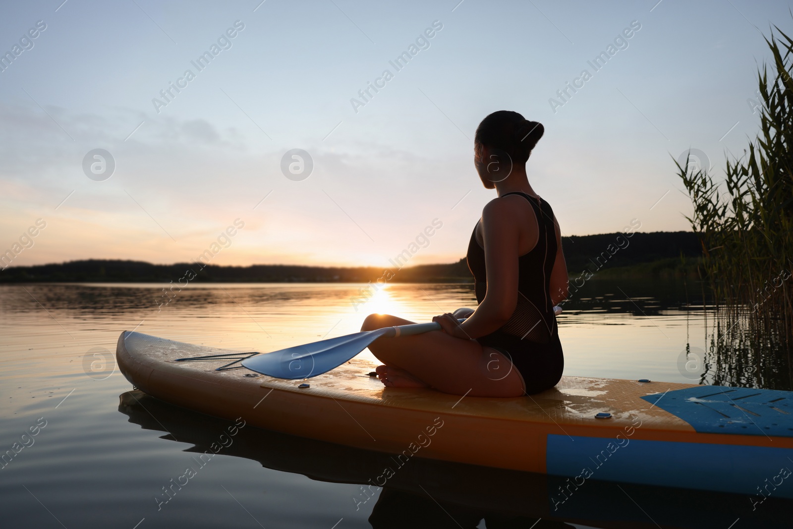 Photo of Woman paddle boarding on SUP board in river at sunset