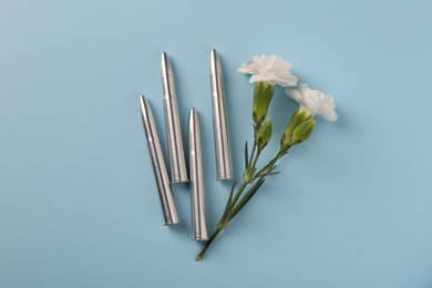Bullets and beautiful flowers on light blue background, flat lay