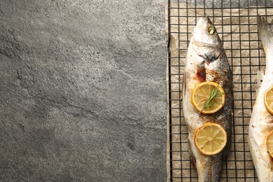 Baked fish with lemon on grey textured table, top view. Space for text