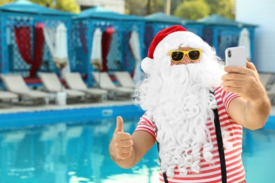 Photo of Authentic Santa Claus taking selfie near pool at resort