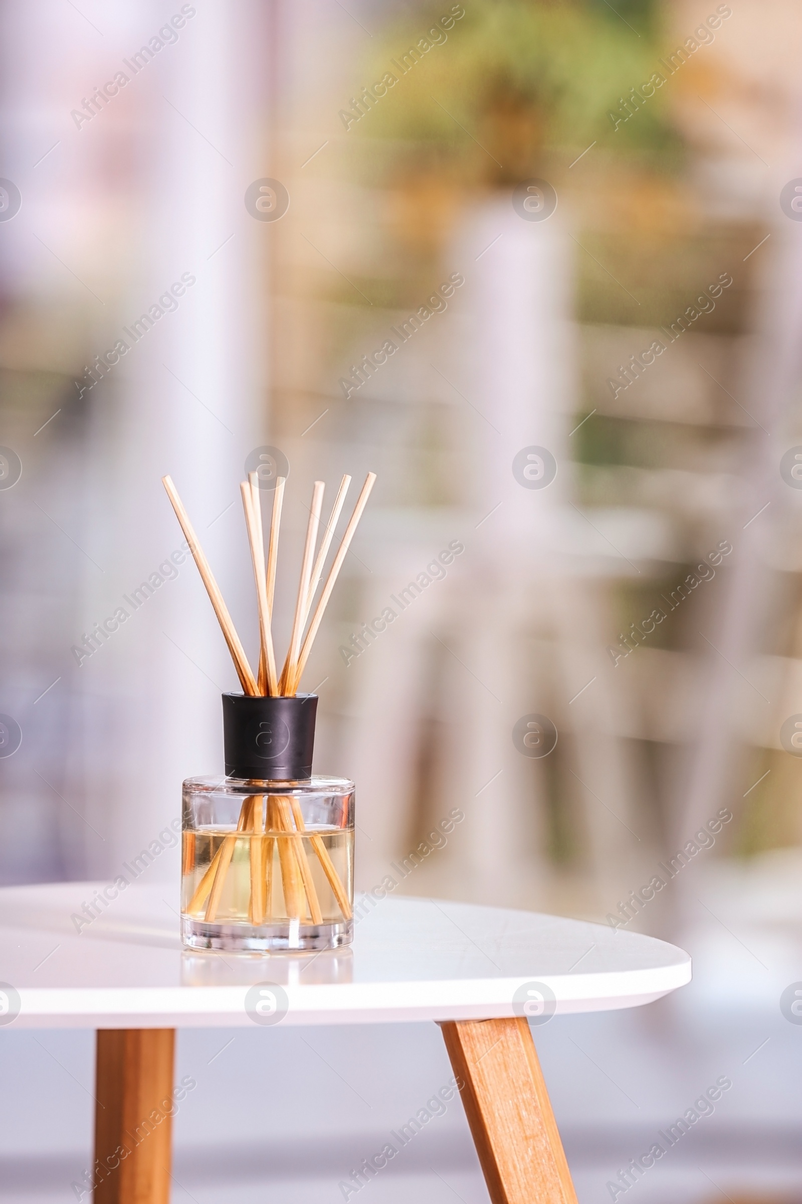 Photo of Aromatic reed air freshener on table against blurred background