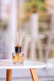 Aromatic reed air freshener on table against blurred background