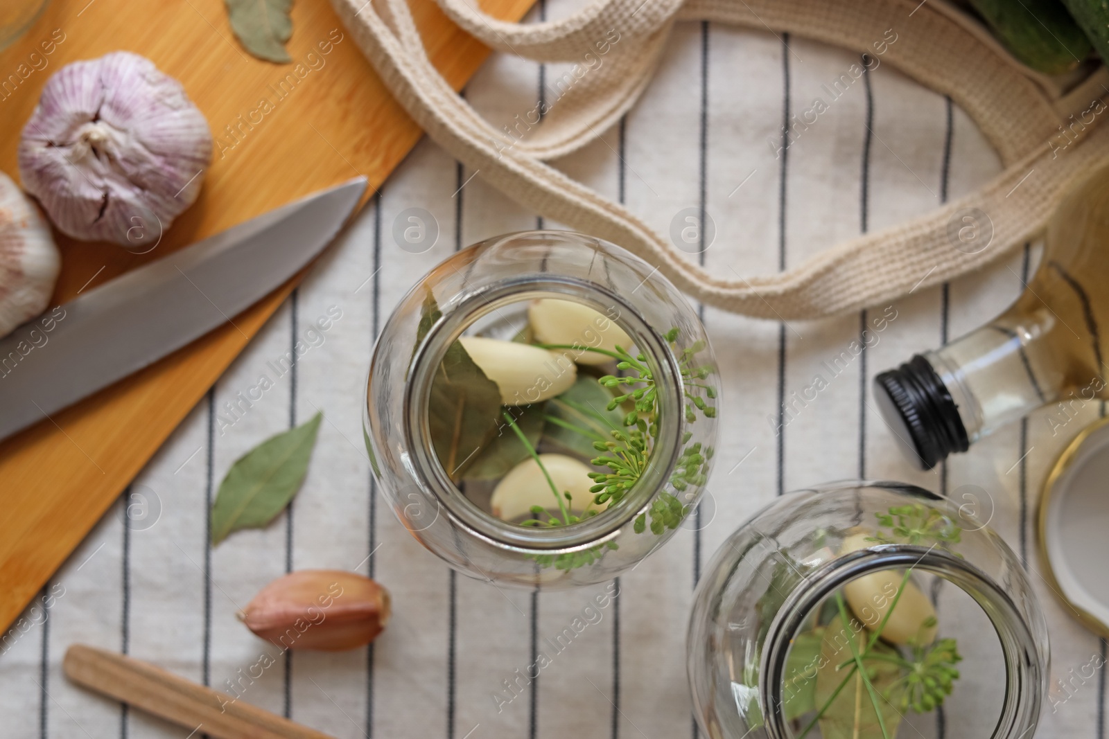 Photo of Empty glass jars and ingredients prepared for canning on tablecloth, flat lay