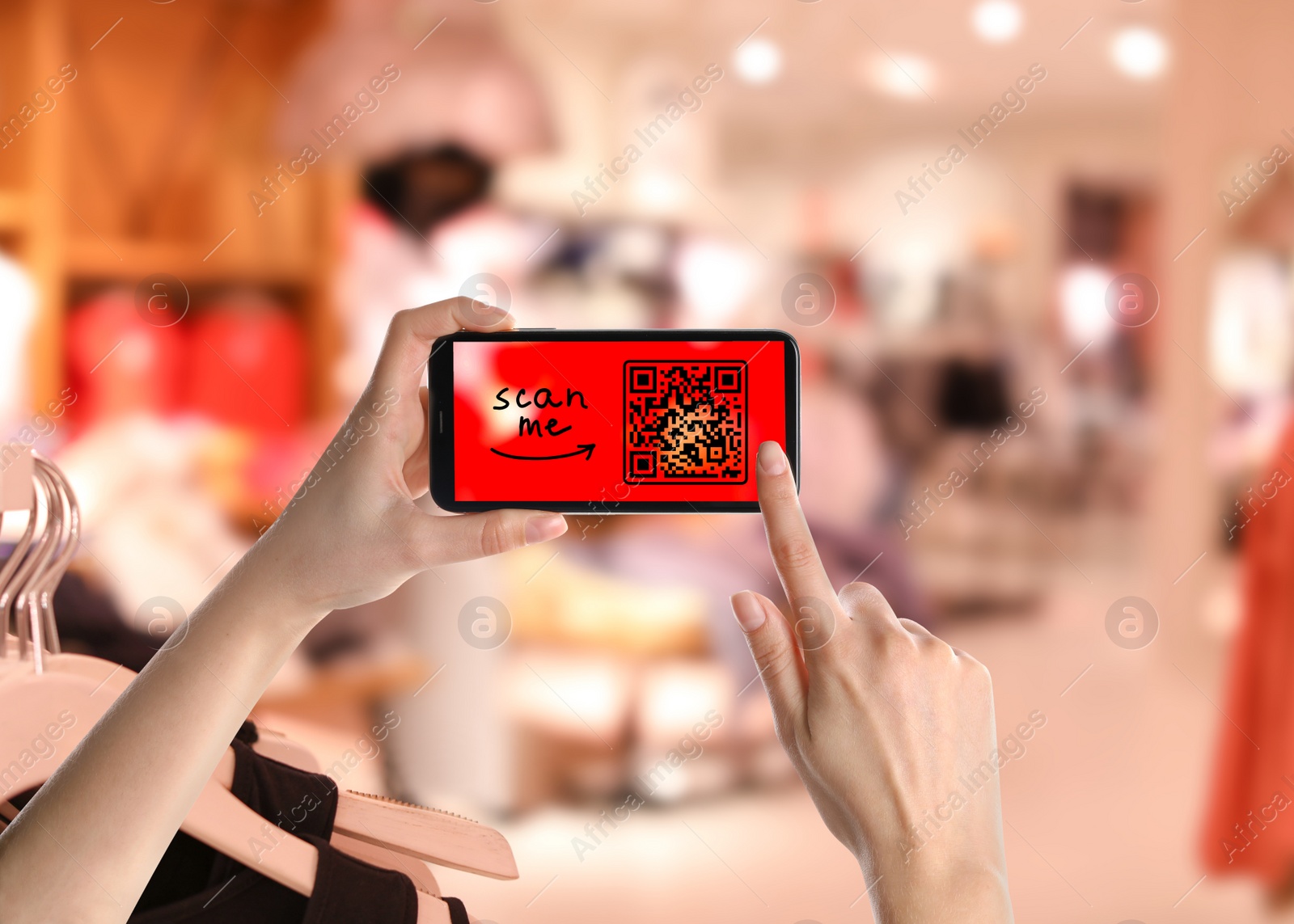 Image of Woman holding smartphone with QR code on screen in store, closeup