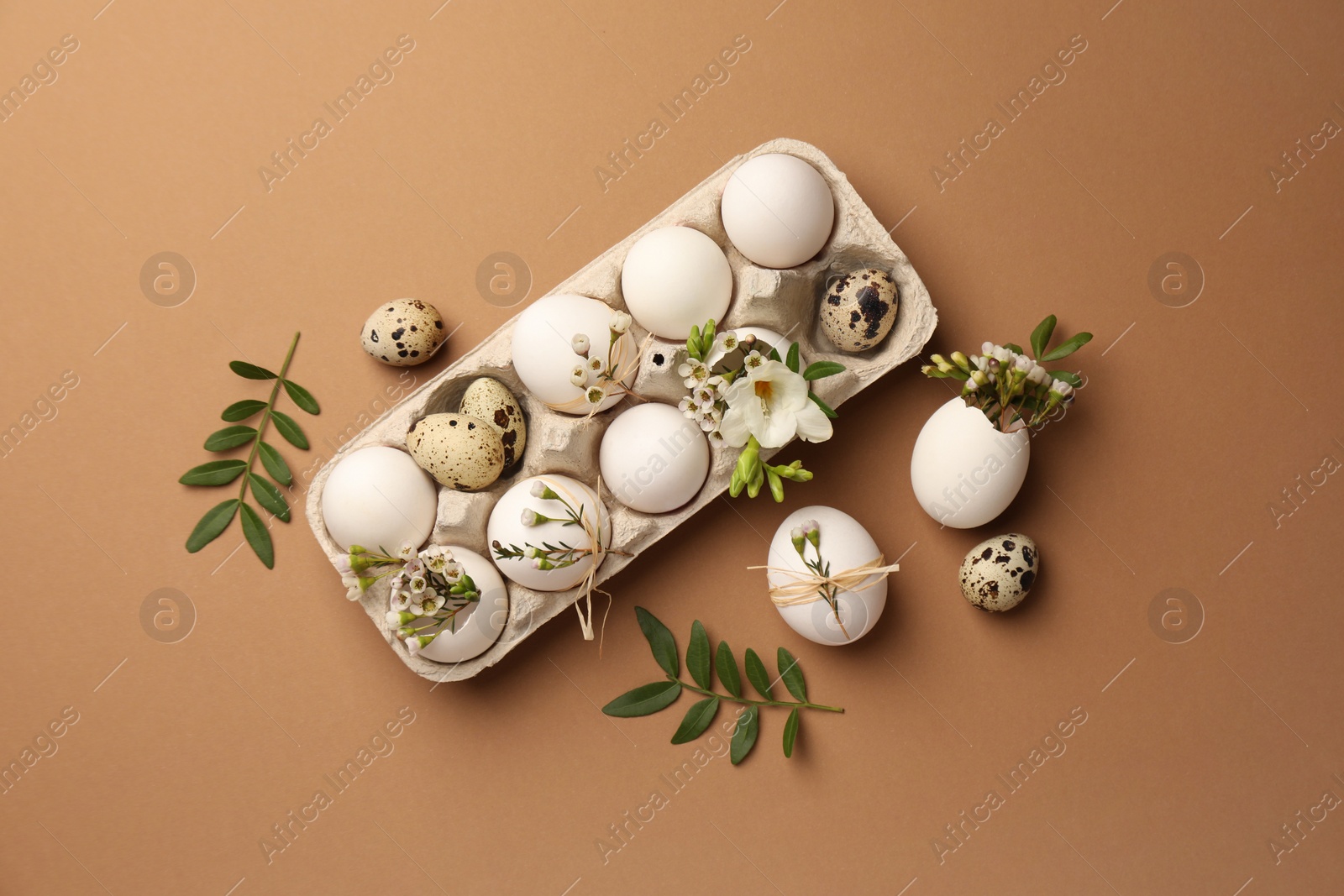 Photo of Festive composition with eggs and floral decor on brown background, flat lay. Happy Easter