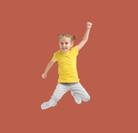 Image of Happy cute girl jumping on dark coral background
